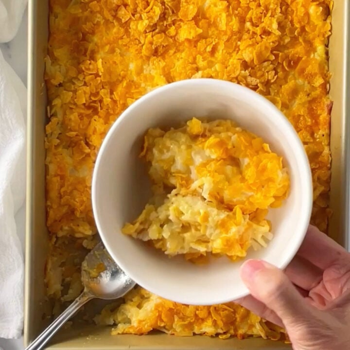 Funeral potatoes casserole served in a white bowl.