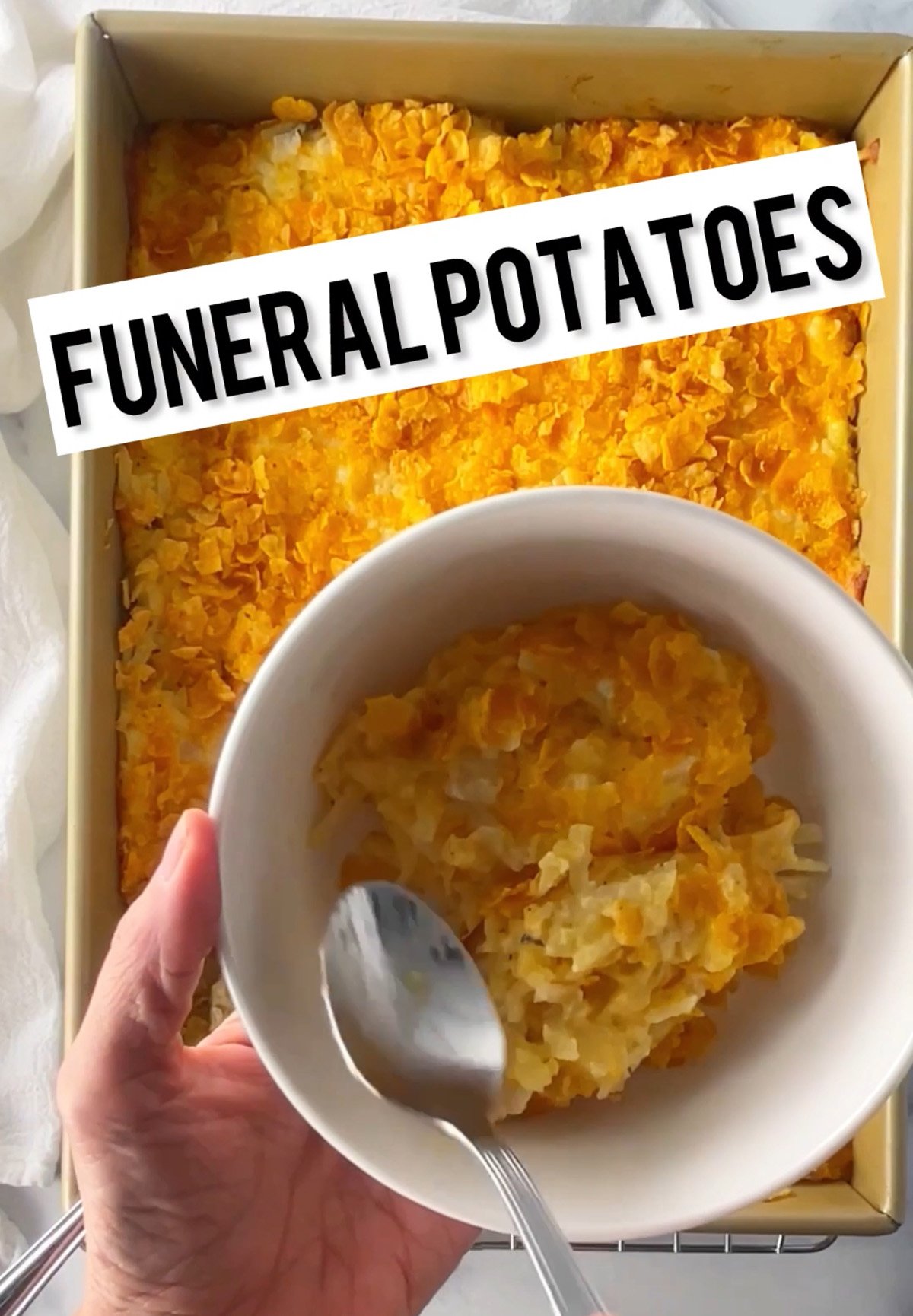 Funeral potatoes in a oblong casserole dish with cornflake topping.