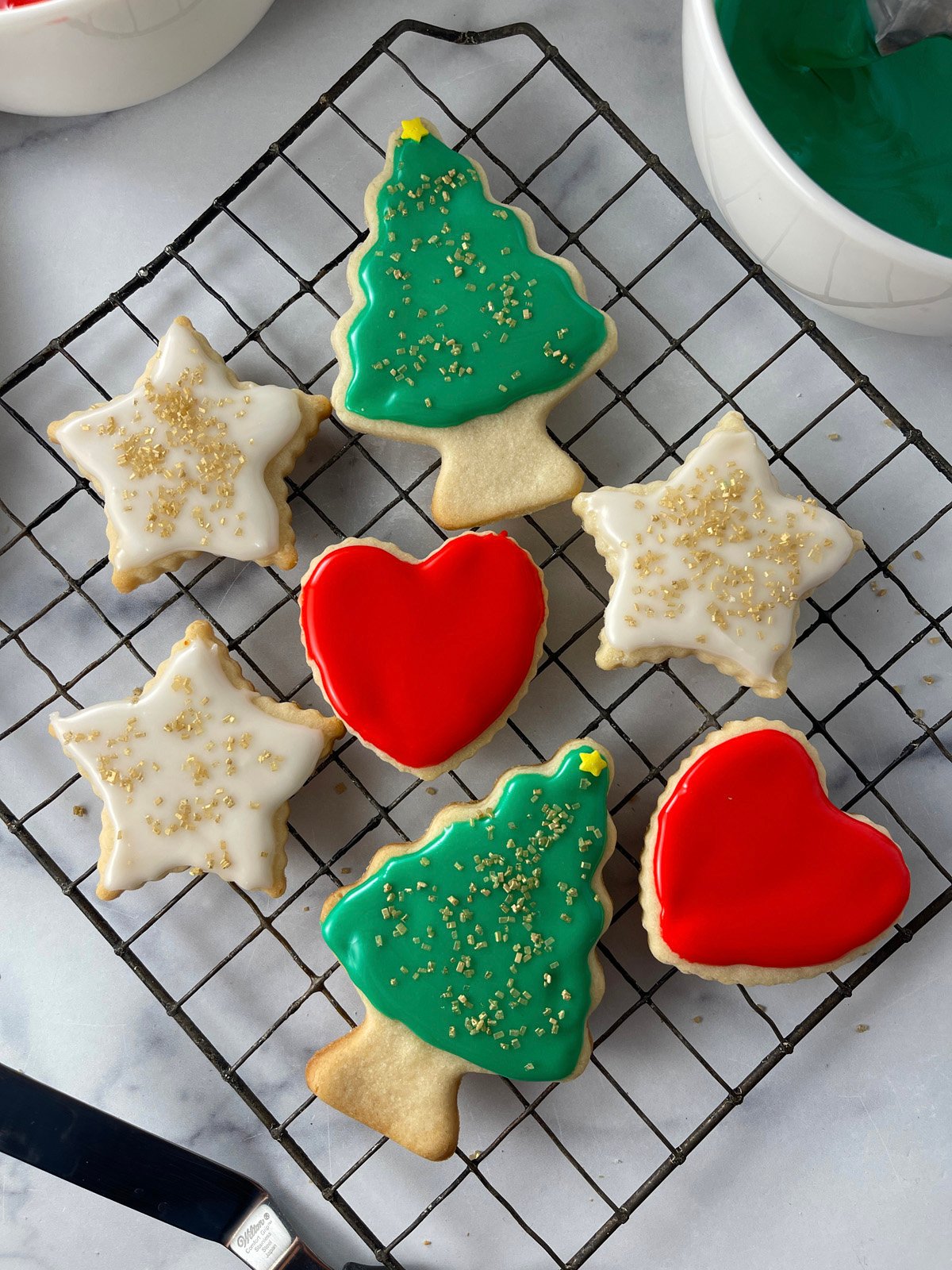 Cooling rack of festive Christmas sugar cookies iced in red and green.