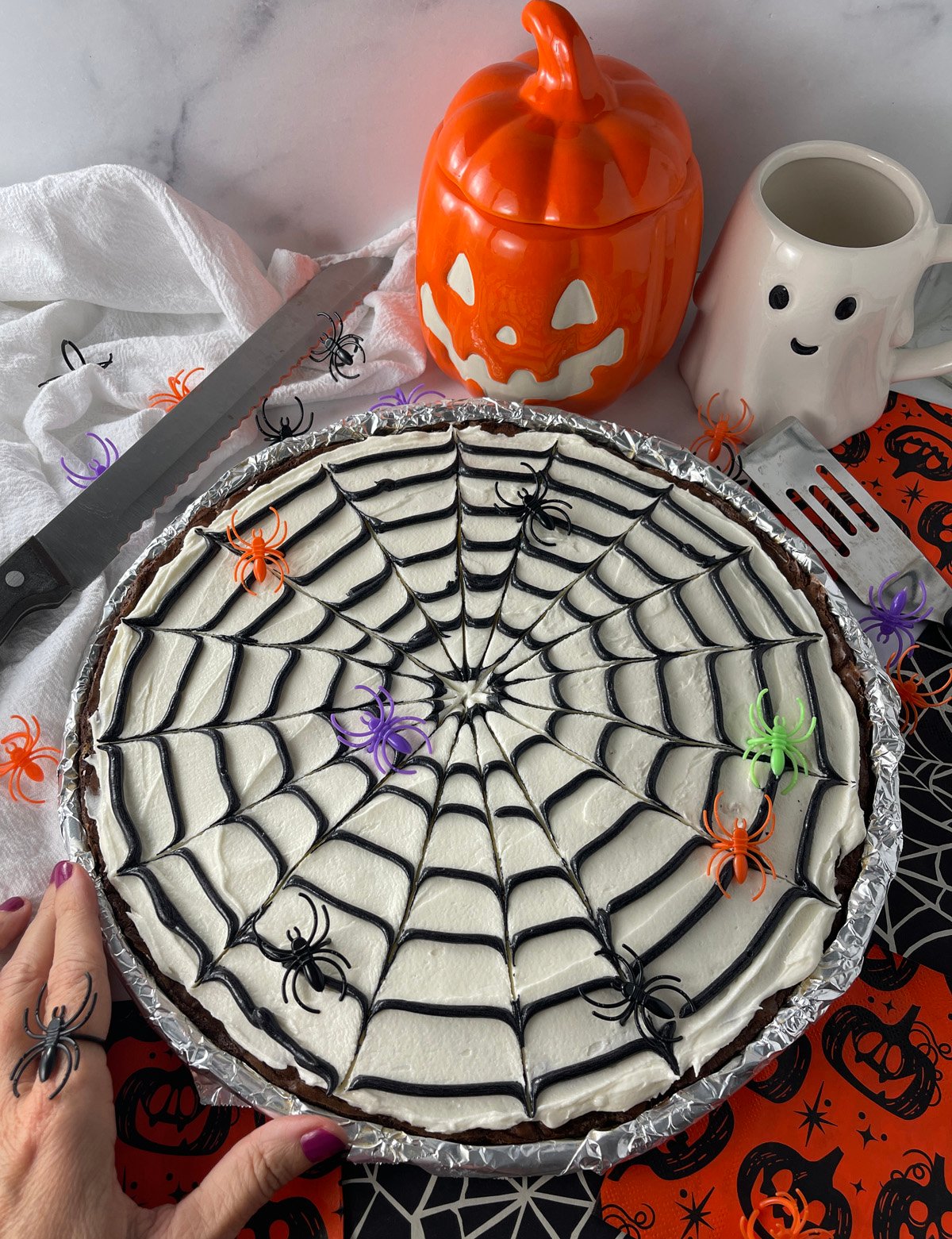 Halloween dessert table featuring a large cookie cake with spider web icing centerpiece.