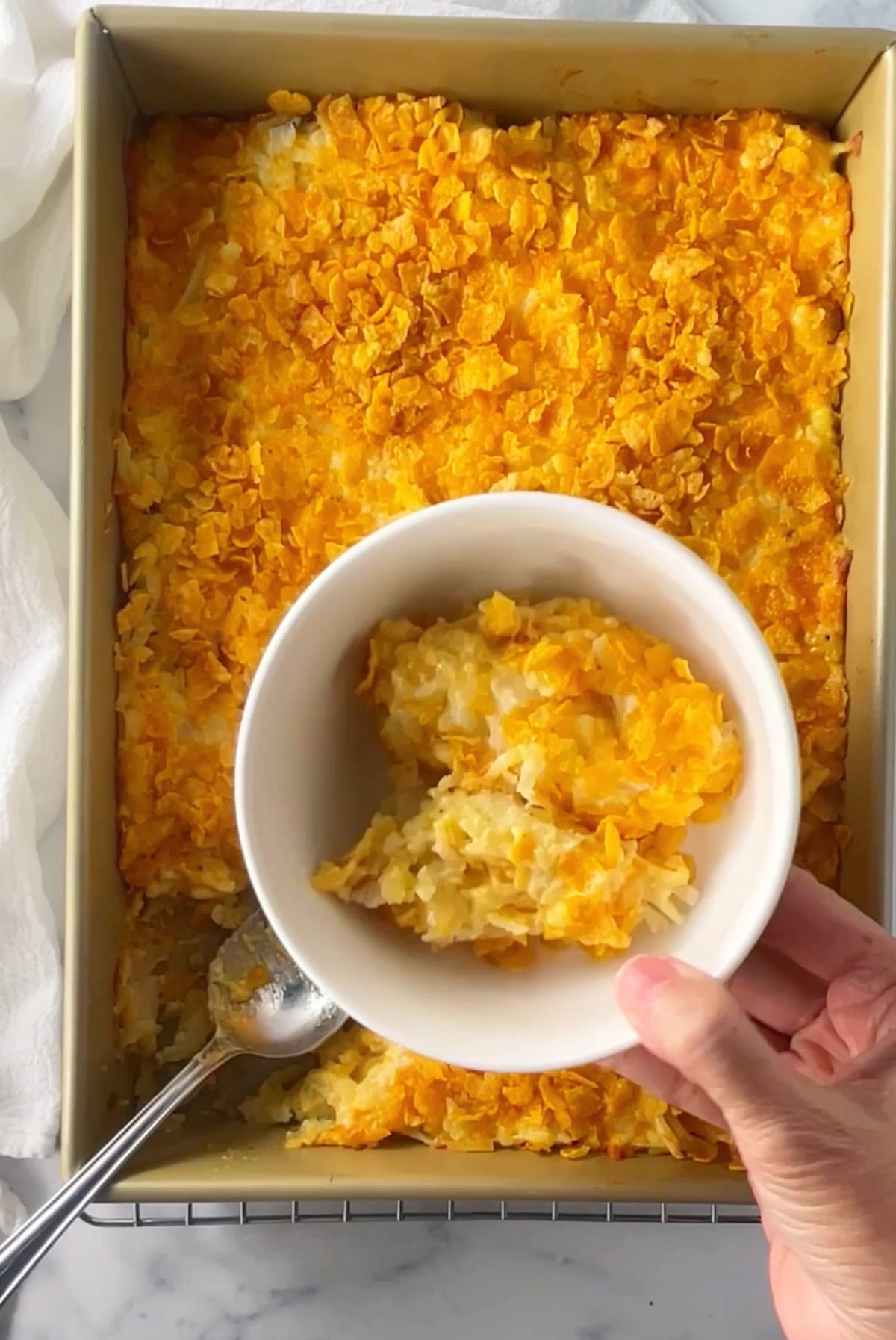 Cheesy hashbrown potatoes in a 13 by 9 baking dish.