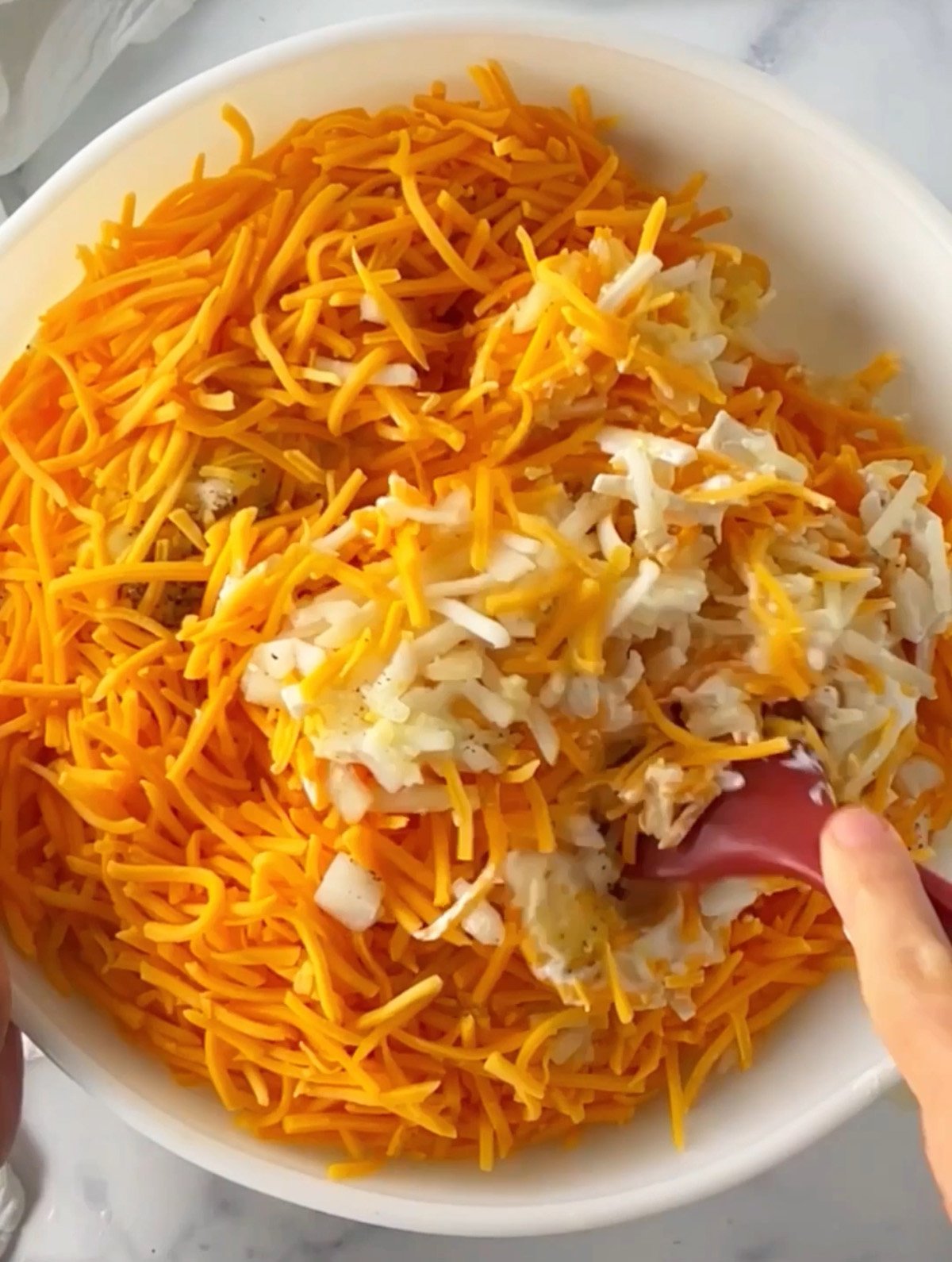 Mixing up all the ingredients in a big bowl to make cheesy hashbrowns casserole dish.