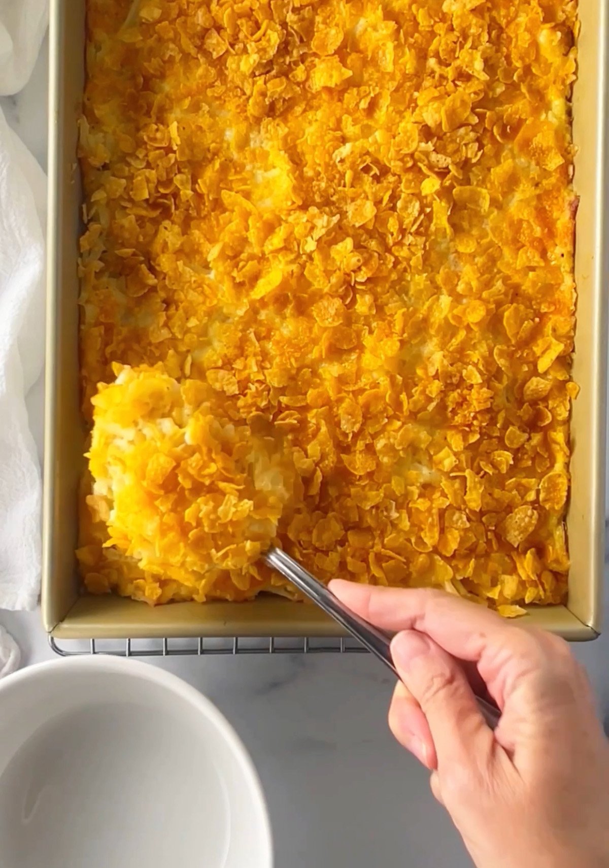 Spooning out casserole into a serving bowl.