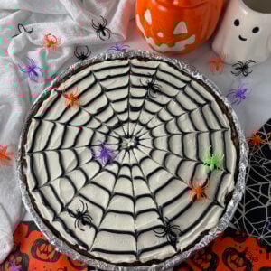 Overhead view of spider web cookie cake on a table with Halloween decorations.