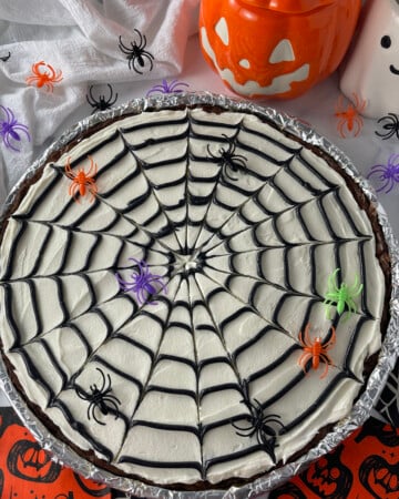 Overhead view of spider web cookie cake on a table with Halloween decorations.