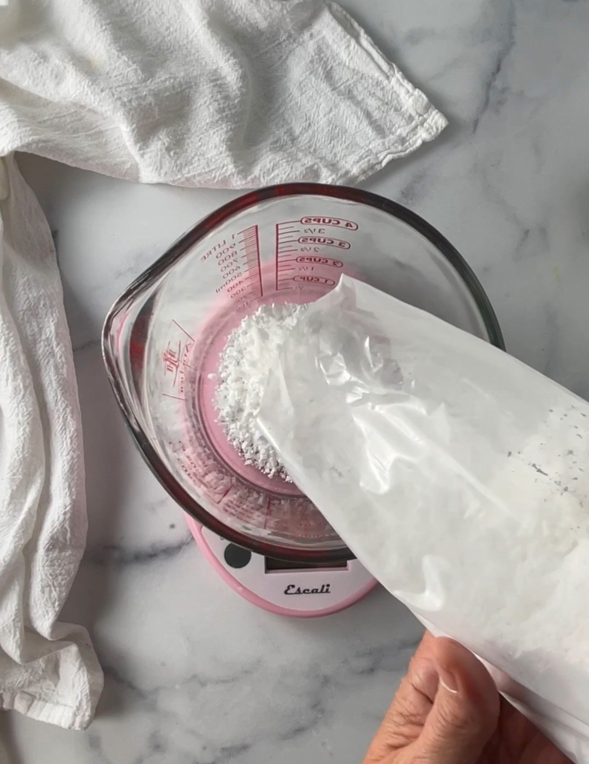 Powdered sugar being weighed on a kitchen scale for making glaze icing.