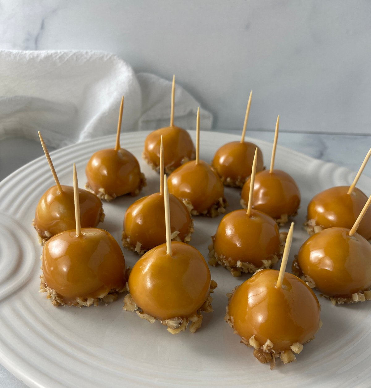 White plate filled with caramel apple cookies topped with drizzled caramel and with little toothpicks on top.