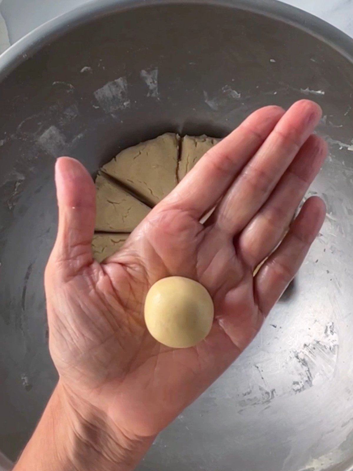 Hand holding a round ball of caramel apple cookie dough ready for baking.