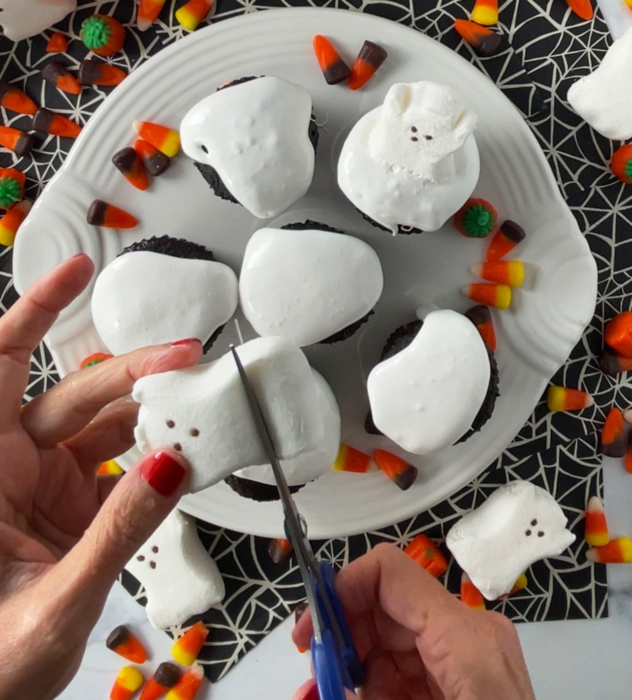 Cutting ghost peeps to place on top of cupcakes.