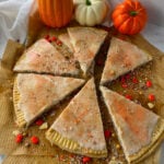 Homemade pumpkin pie pop tarts cut into pie shapes on parchment paper.