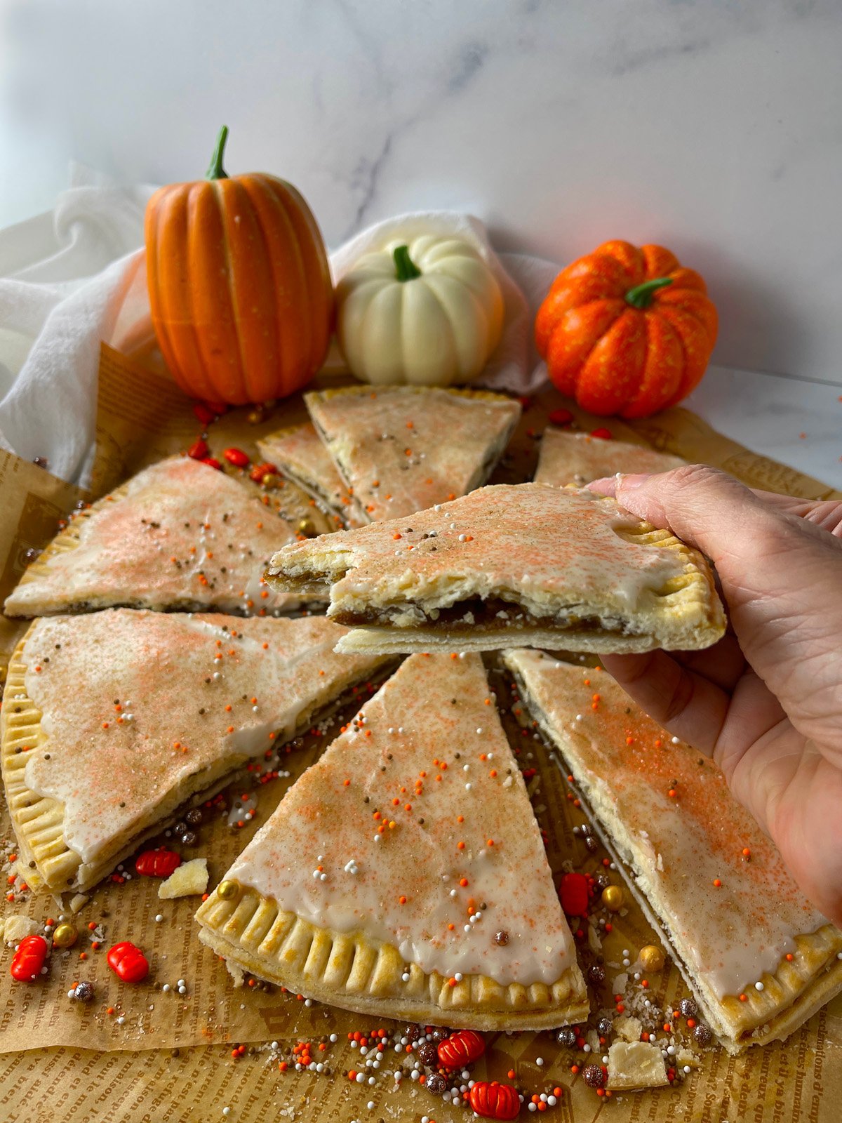 Hand holding pumpkin pie poptart to show inside filling.