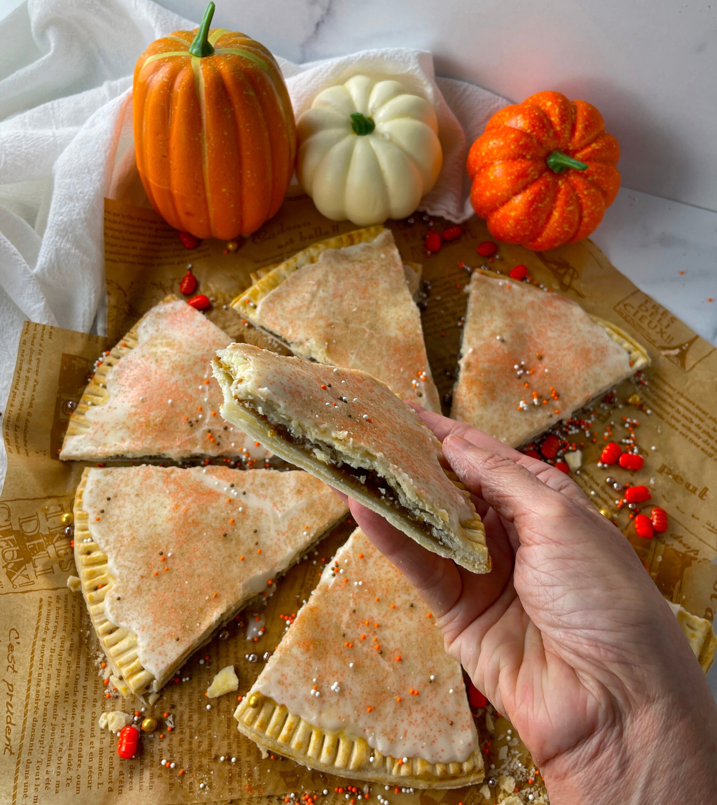 Hand holding homemade pumpkin pie pop tart triangle.