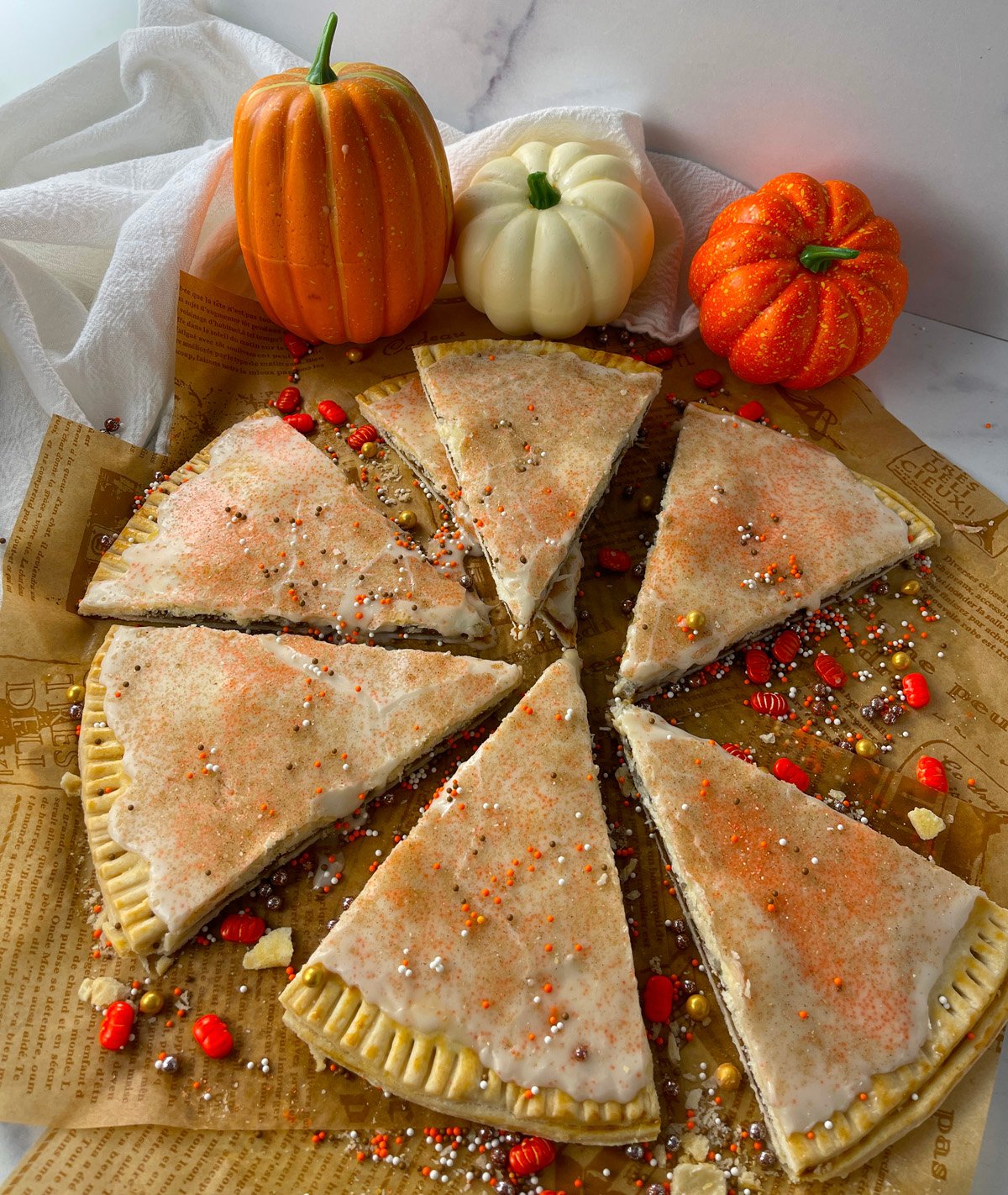 Easy pumpkin pop tarts in the shape of a pizza, cut into triangles with sprinkles.