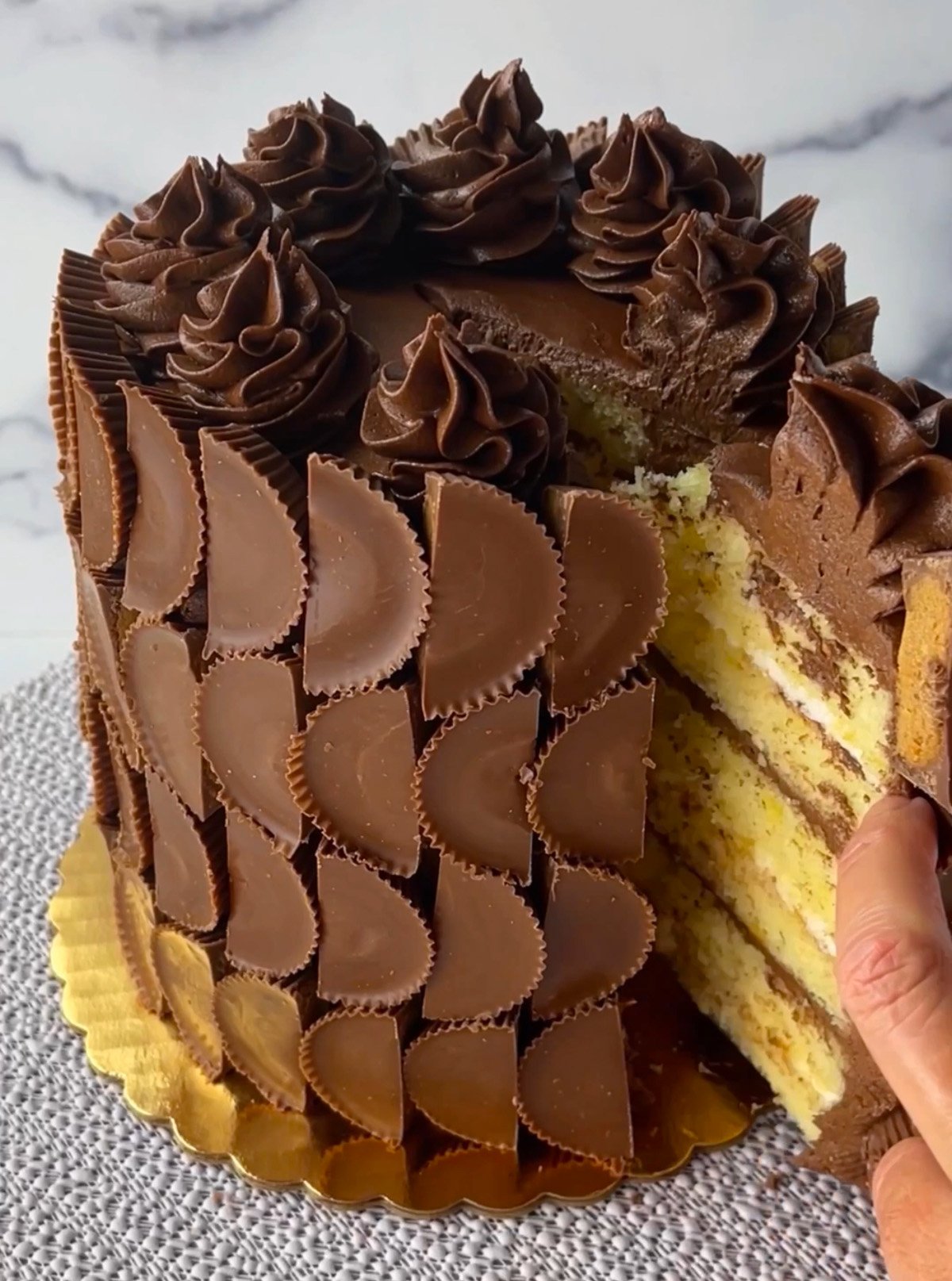 Slicing a cake covered in Reese's peanut butter cups.