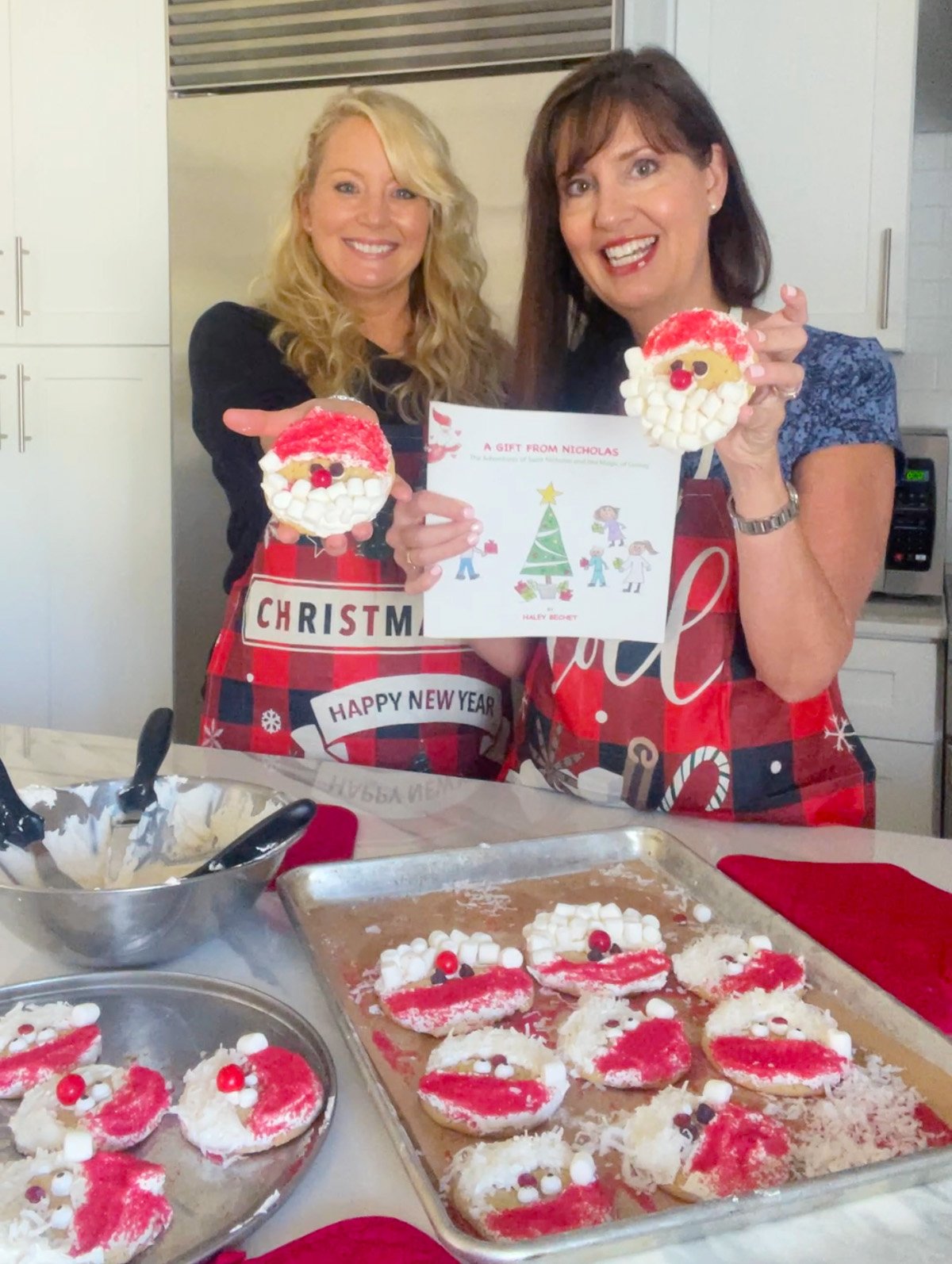 Lise and Haley holding and showing their decorated Santa cookies.