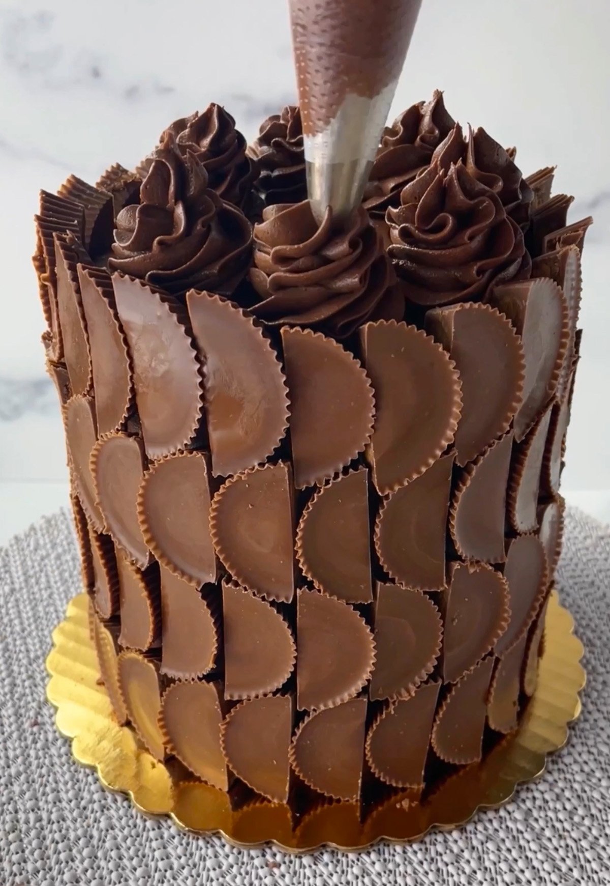 Using a 1m tip to pipe chocolate frosting on cake.