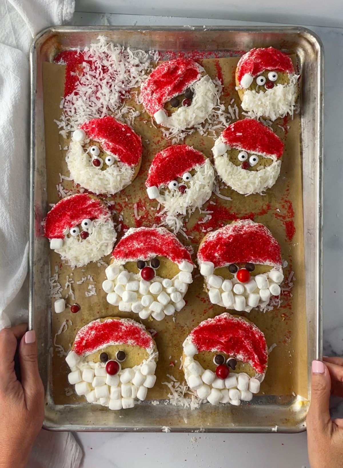 Baking sheet filled with frosted gluten-free Santa cookies.