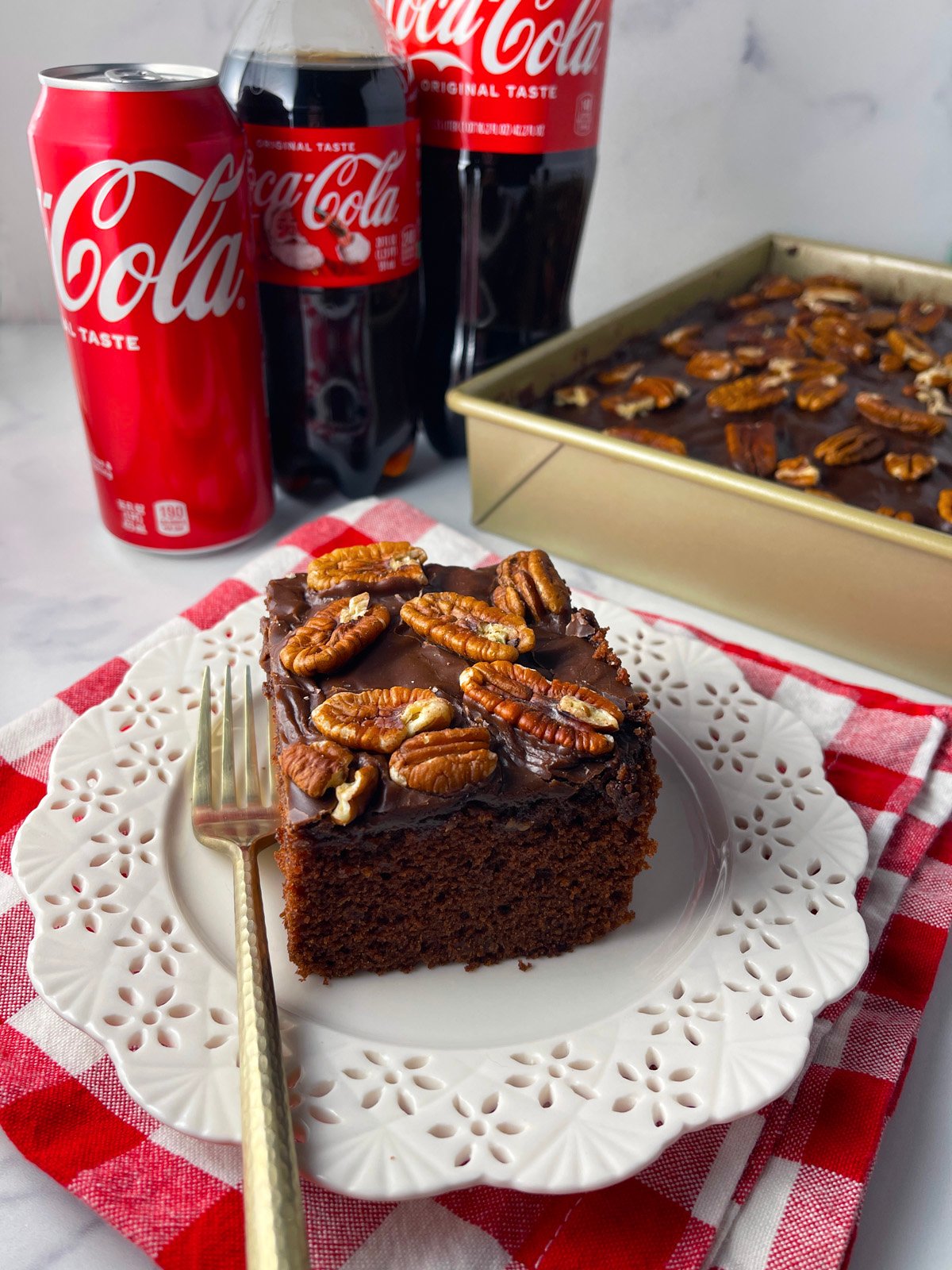 Slice of coca cola cake on white plate with coke can.