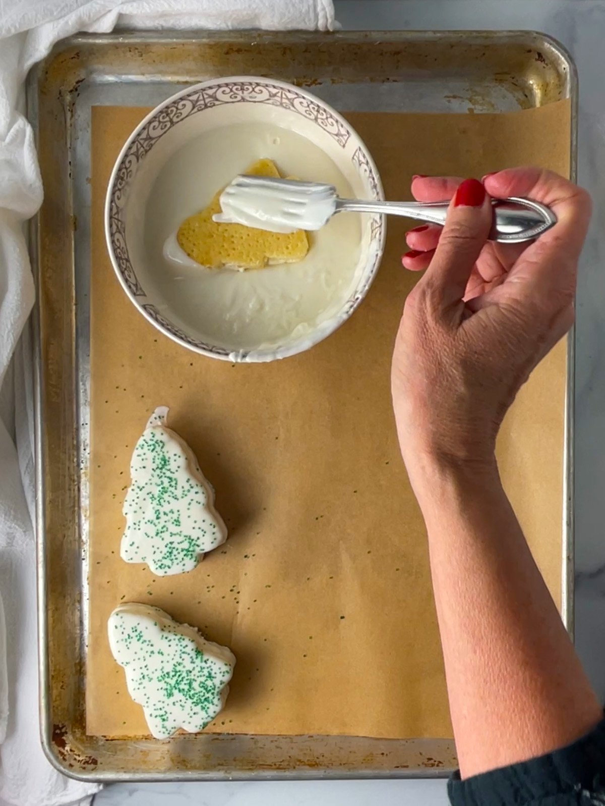 Dipping Christmas tree cakes in melted white candy melts.
