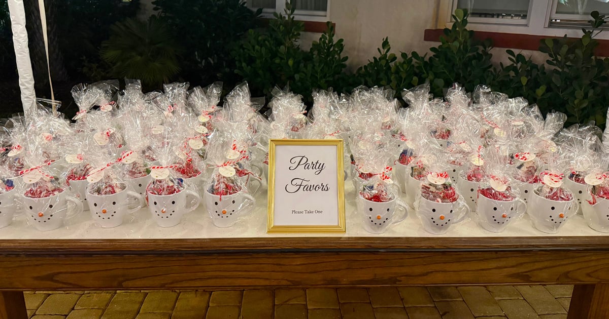 Snowman mug party favors filled with candy and Little Debbie tree cake.