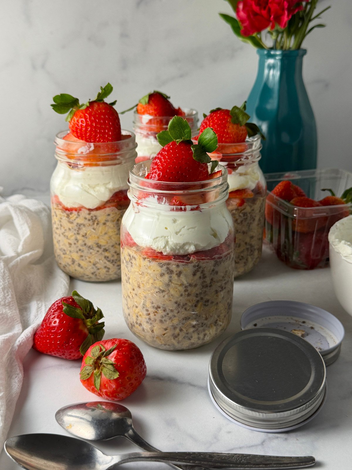Layered strawberry overnight oats with chia seeds, creamy Greek yogurt, fresh berries, and honey in a glass mason jar.