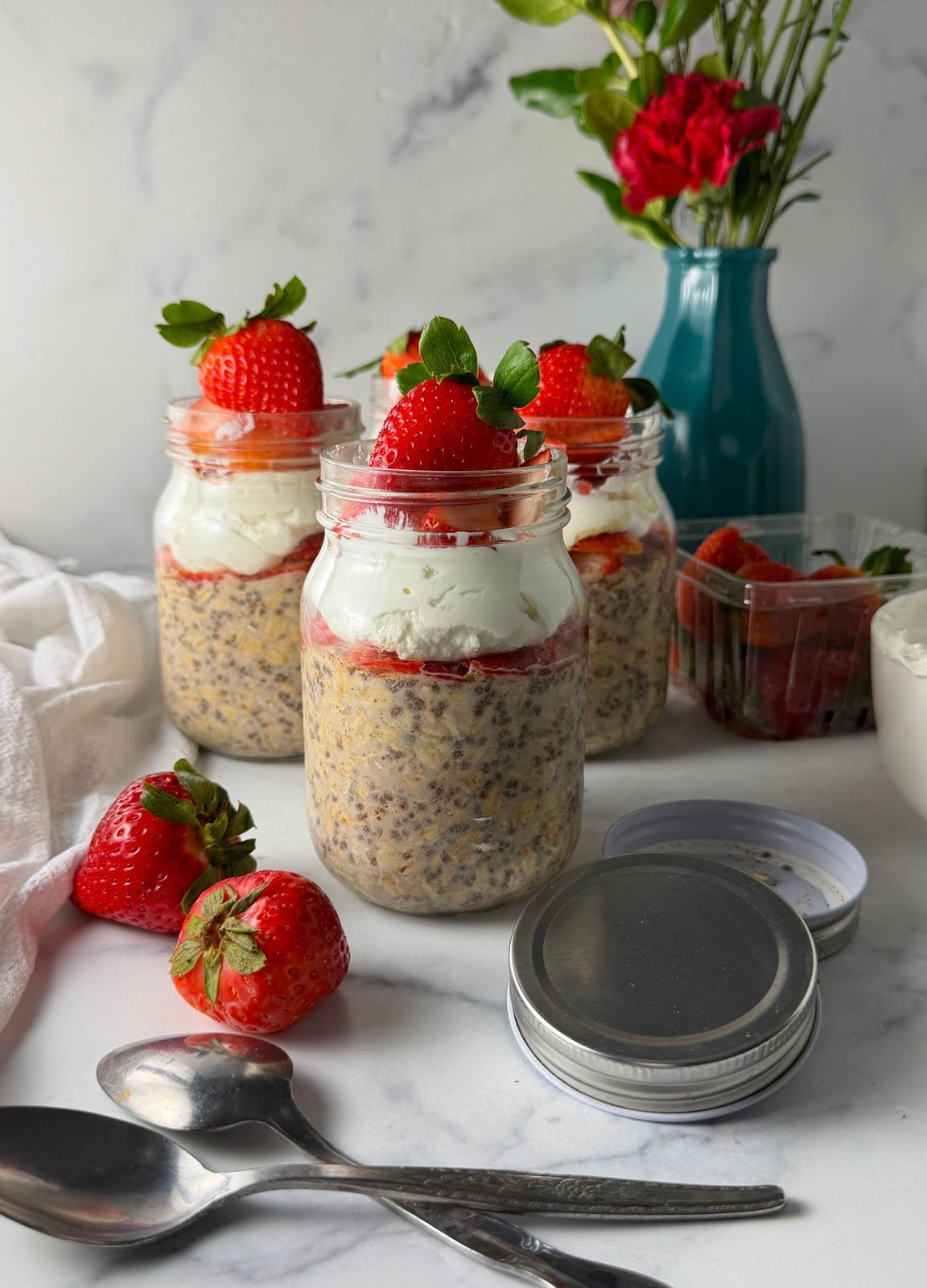 Layered strawberry overnight oats with chia seeds, creamy Greek yogurt, fresh berries, and honey in a glass mason jar.