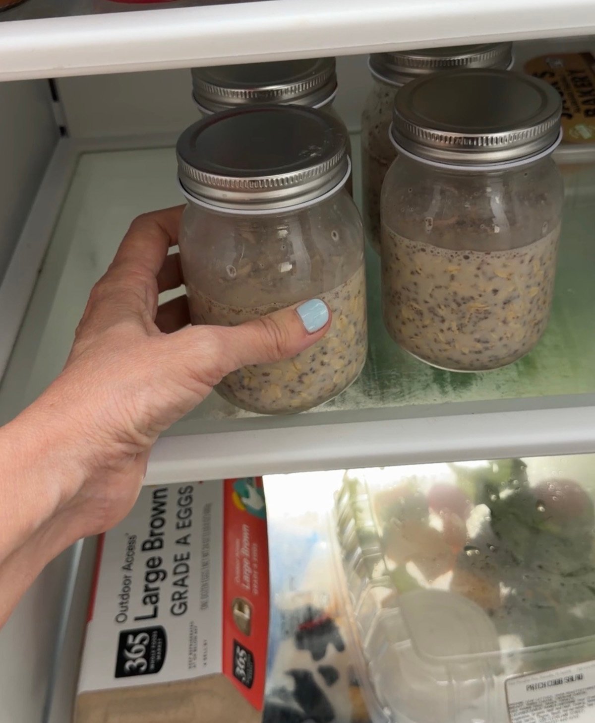 Putting the prepared jars of overnight oats into the fridge.