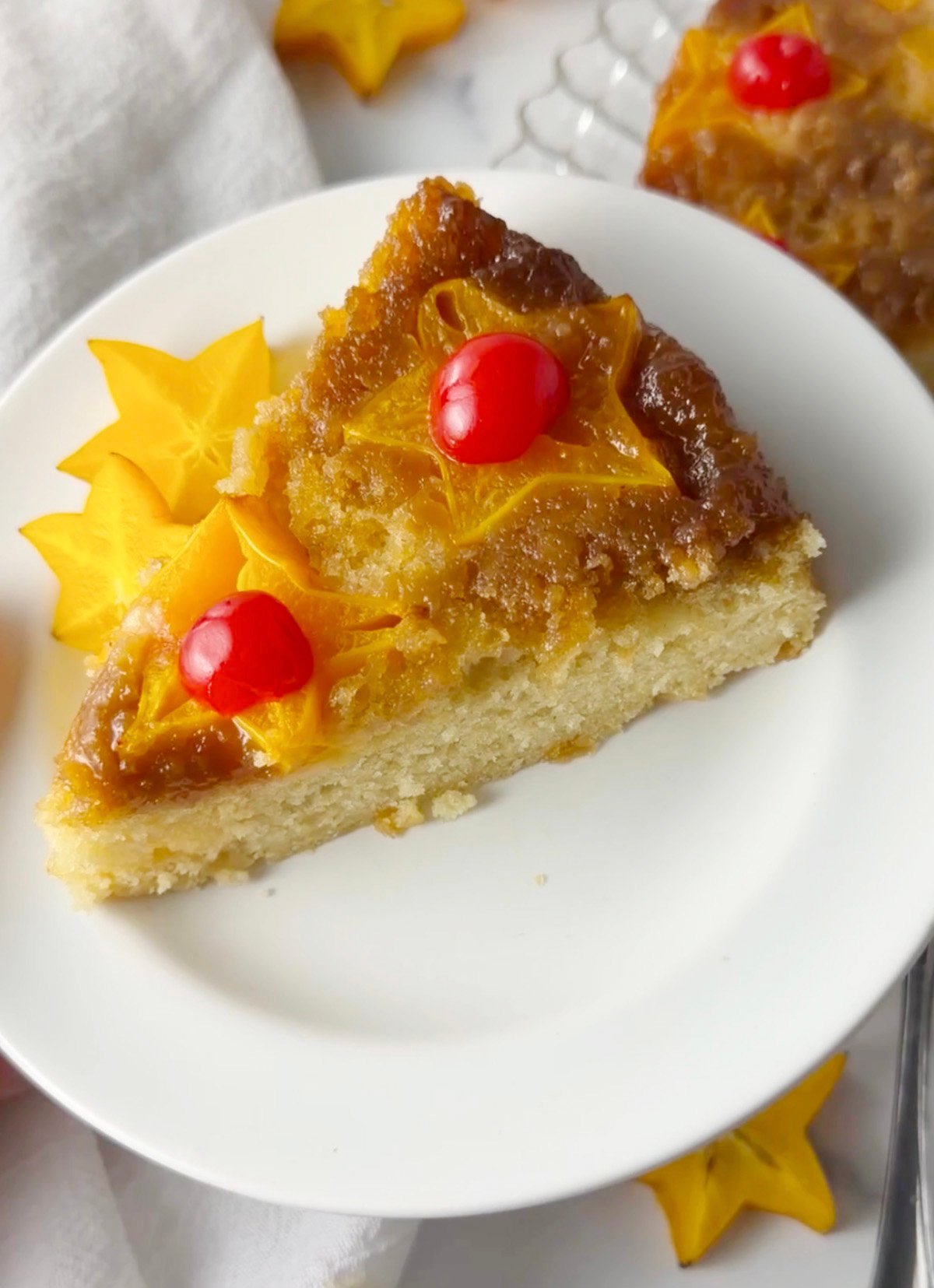 Slice of star fruit upside down cake on a white plate.