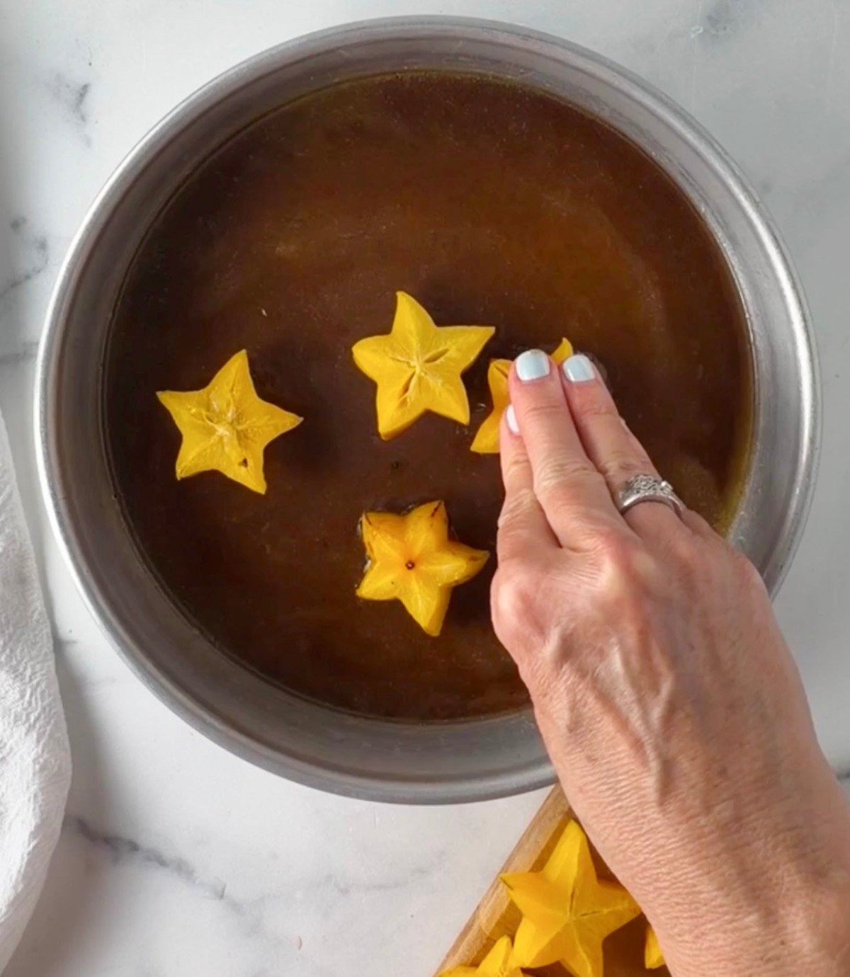 Star fruit slices in cake pan with brown sugar butter mixture.