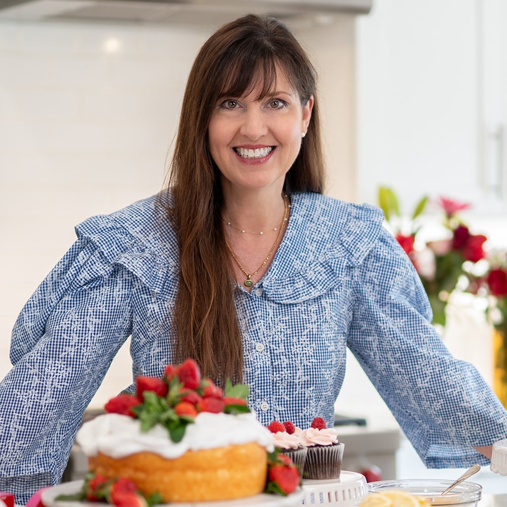 Lise headshot in a blue shirt with a cake.