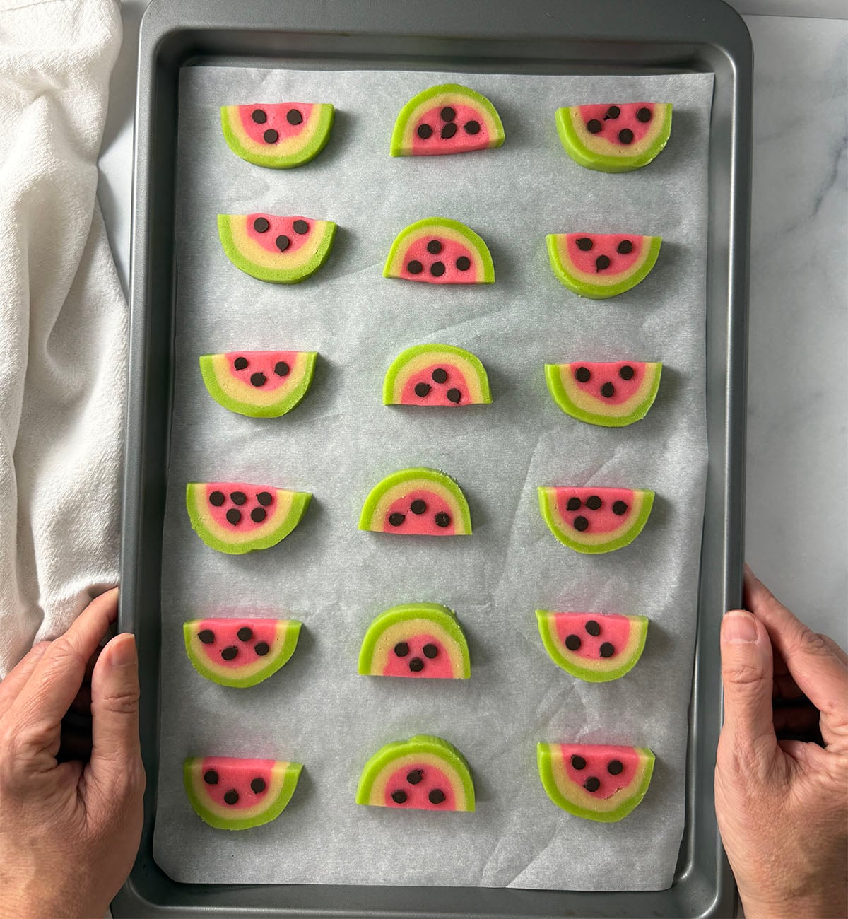 Watermelon cookie slices on cookie sheet.
