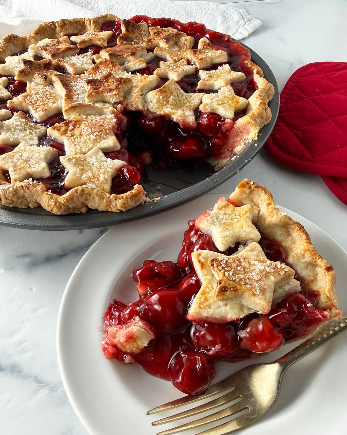 Homemade cherry pie with slice served on plate.