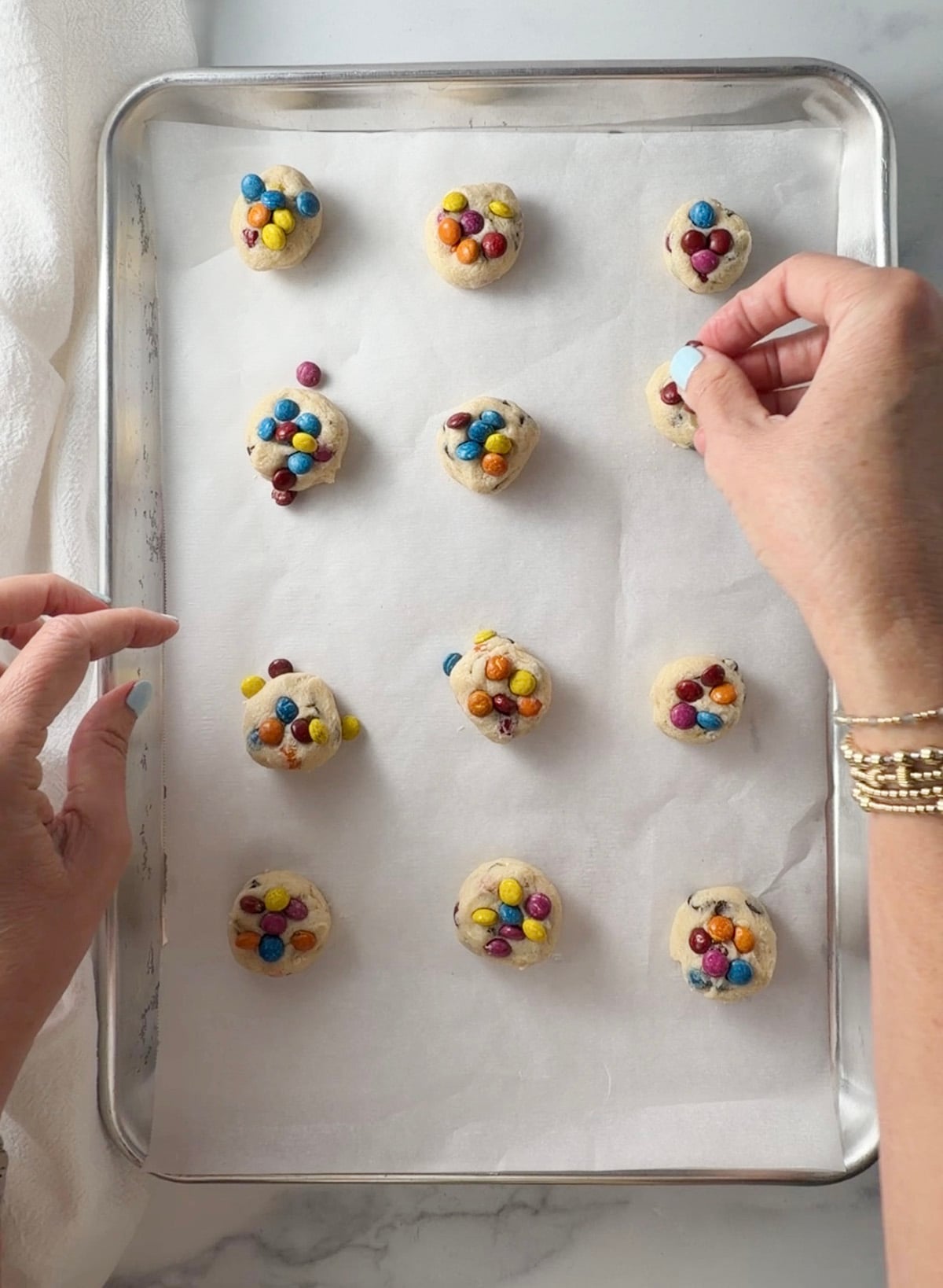 Cookie dough on a cookie sheet with rainbow m&m candies.