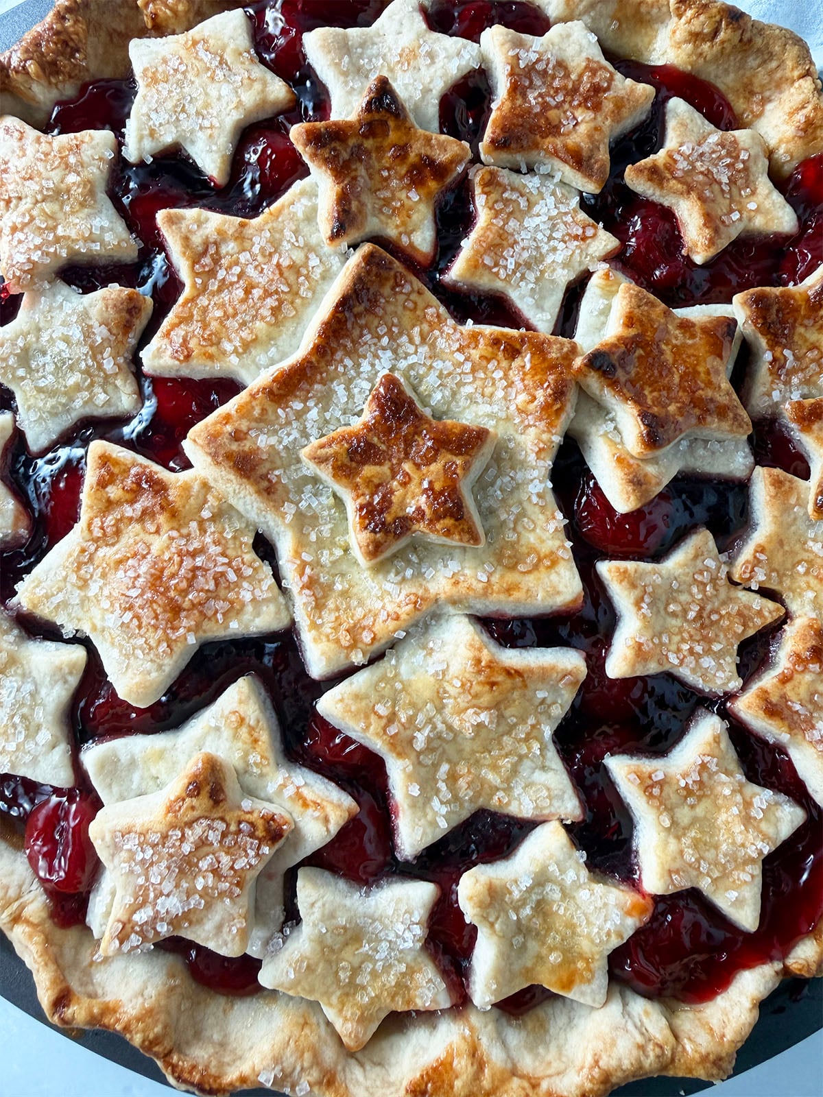 Homemade pie crust stars on top of cherry pie.