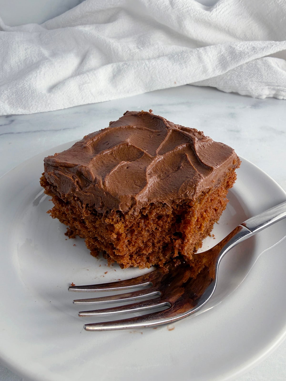 Slice of chocolate cake on a white plate.