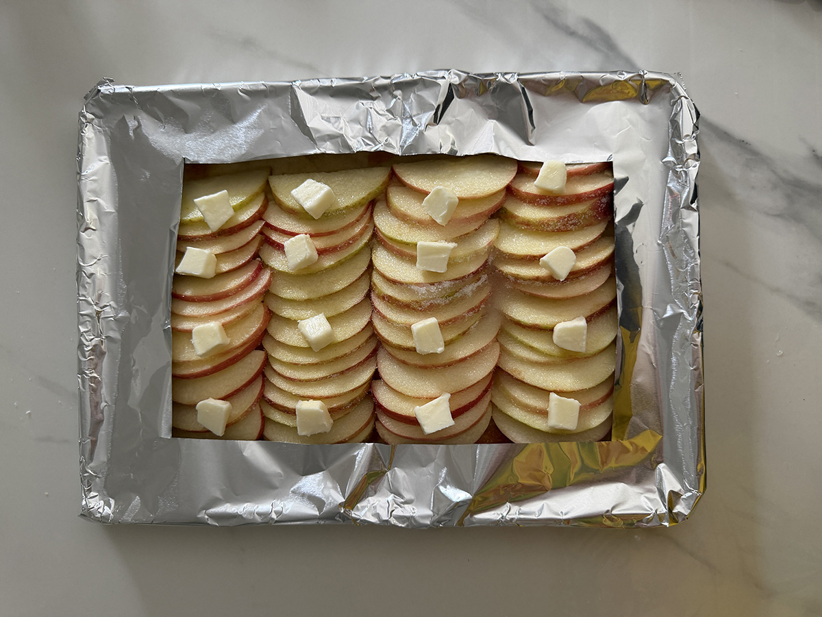 Apple tart on baking pan with foil ready for the oven.