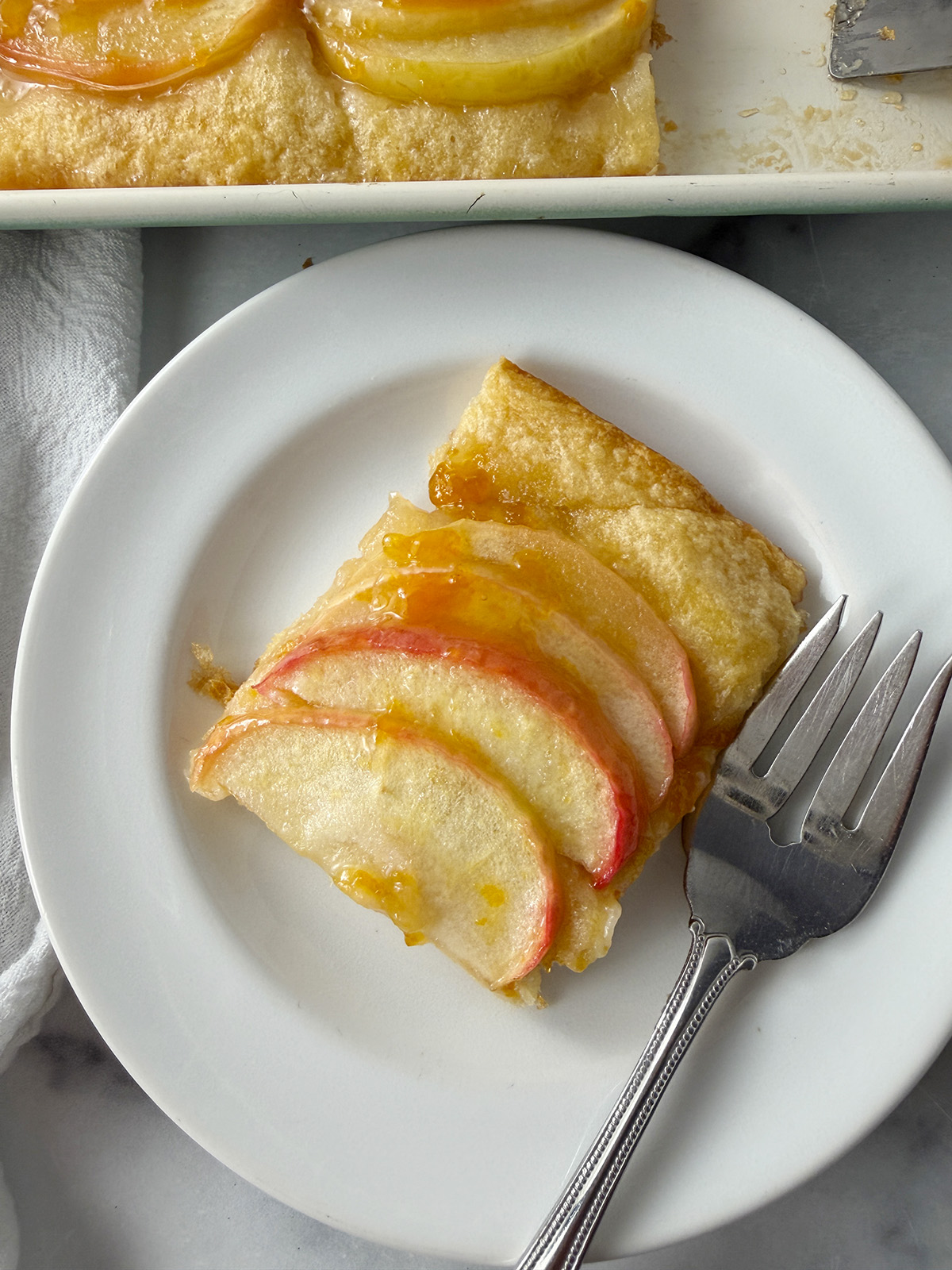 Apple tart served on a white plate with fork.