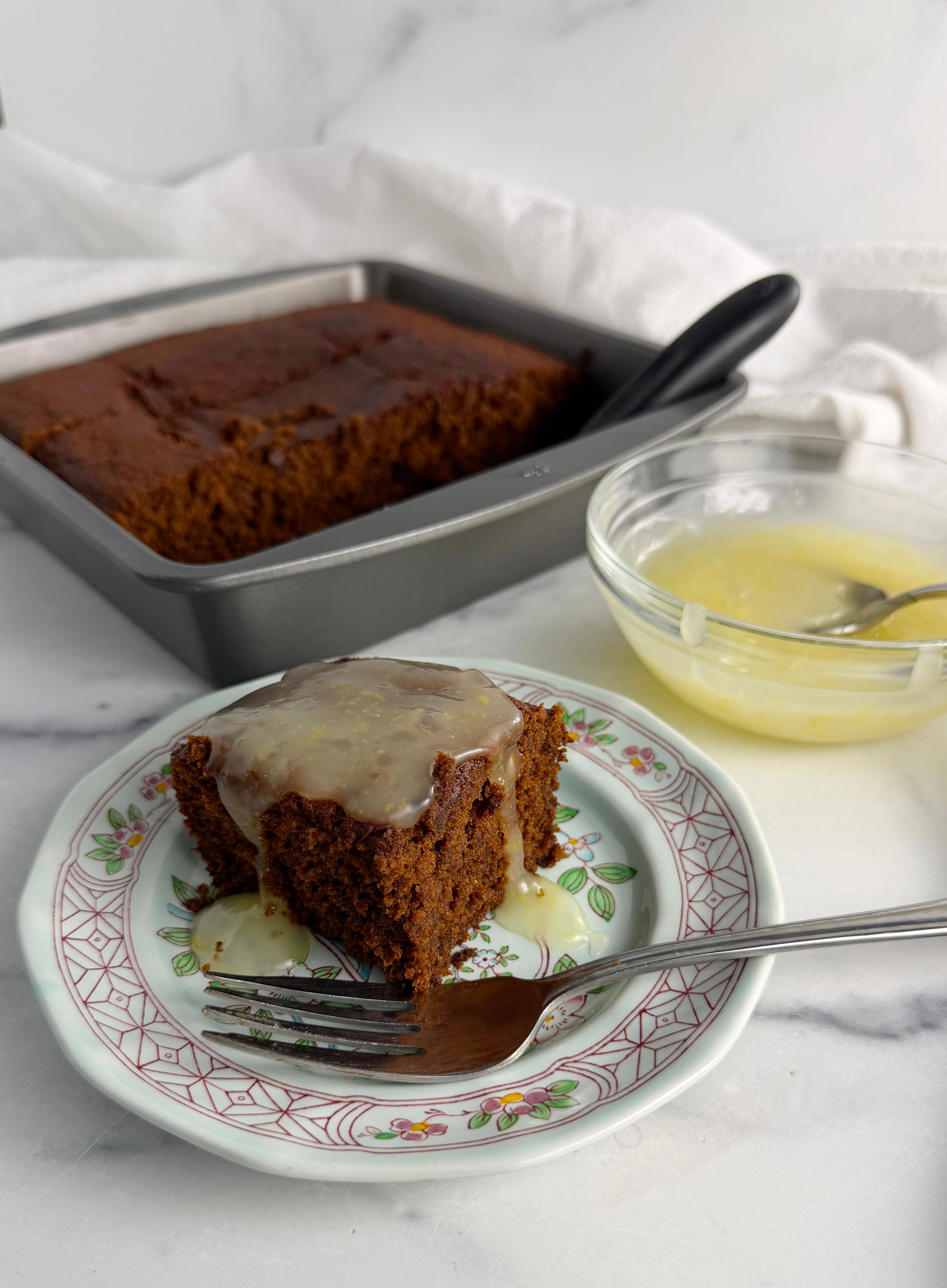 Old fashioned gingerbread with lemon sauce on a plate with fork.