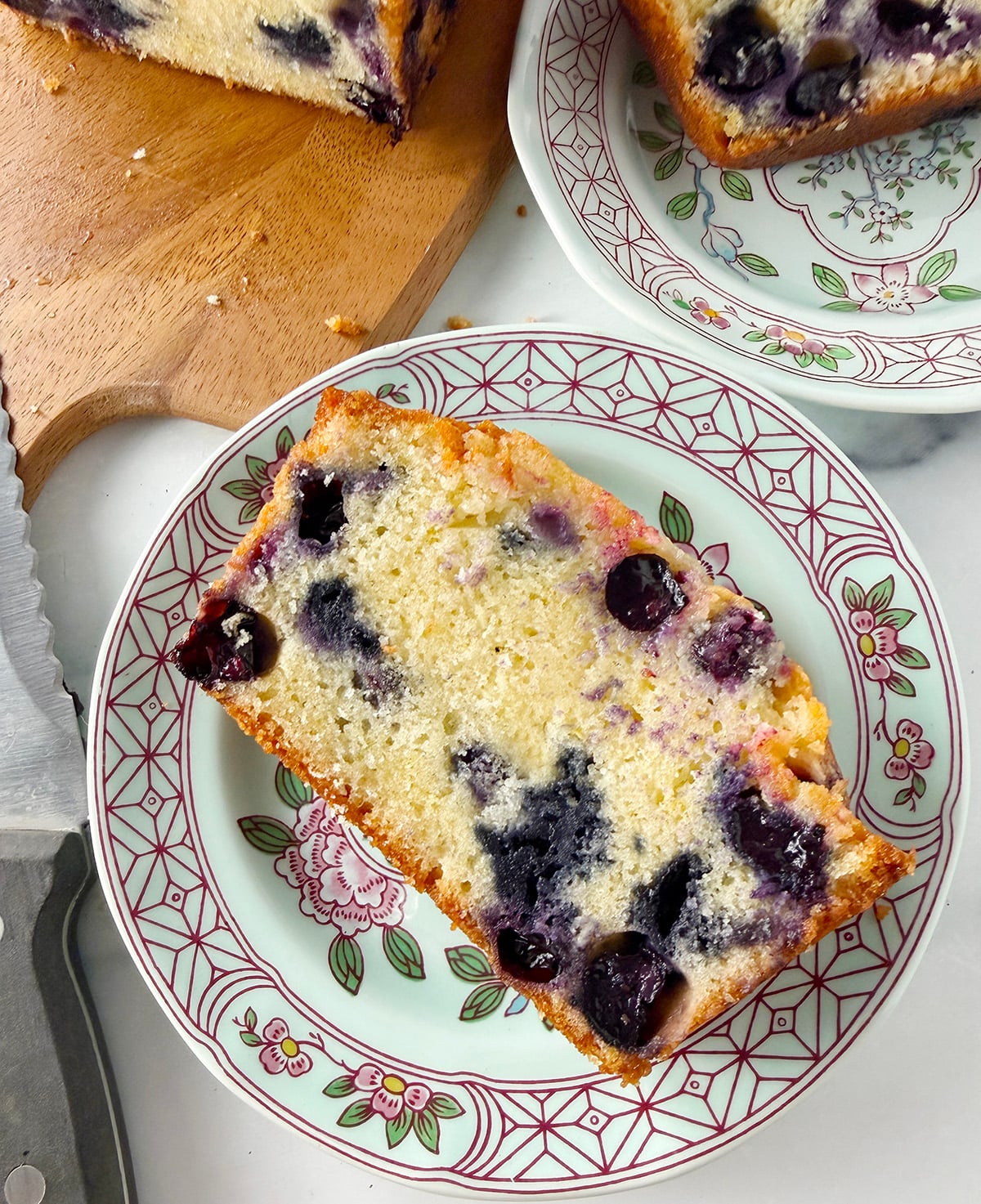 A piece of lemon blueberry bread on floral small dessert plate.